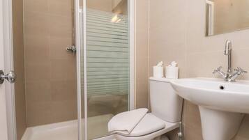 A bathroom with a glass shower enclosure, a toilet, and a sink.