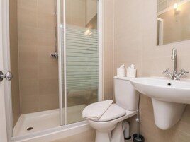 A bathroom with a glass shower enclosure, a toilet, and a sink.