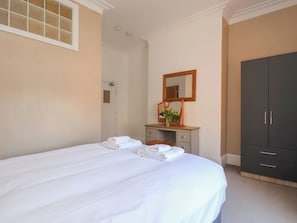 Un dormitorio con cama, cómoda, espejo y armario.