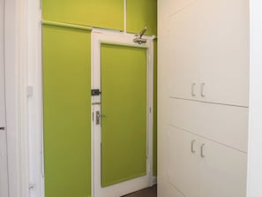 Una habitación con una puerta verde, armarios blancos y una puerta blanca.