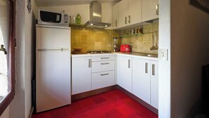 Una cucina compatta con pensili bianchi, un forno a microonde, un tostapane rosso e un piano cottura a gas.