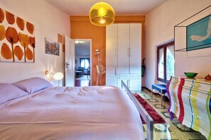 Ein Schlafzimmer mit Bett, Kleiderschrank, Kommode und Fenster.