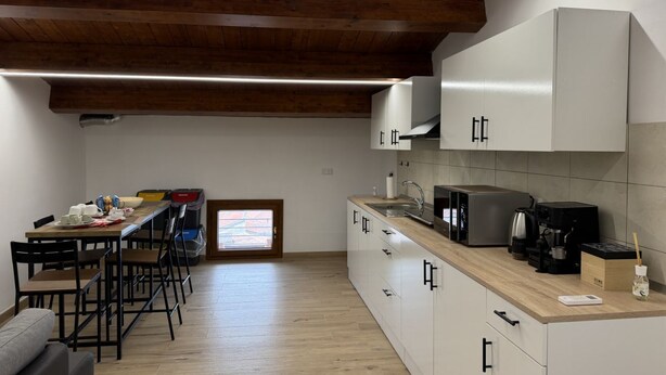 A modern kitchen with white cabinets, a wooden countertop, and a dining area with chairs. - Holiday home in the historic centre of Fuscaldo Paese (Fuscaldo)