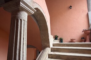 Una scala in pietra con una parete rosa, una colonna e piante in vaso.