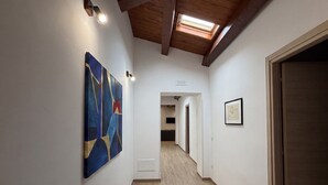 A hallway with a skylight, wooden beams, a painting, and a framed picture on the wall. - Holiday home in the historic centre of Fuscaldo Paese (Fuscaldo)
