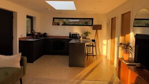 Une cuisine moderne avec un îlot central, un coin repas avec un canapé et un téléviseur posé sur un meuble en bois.