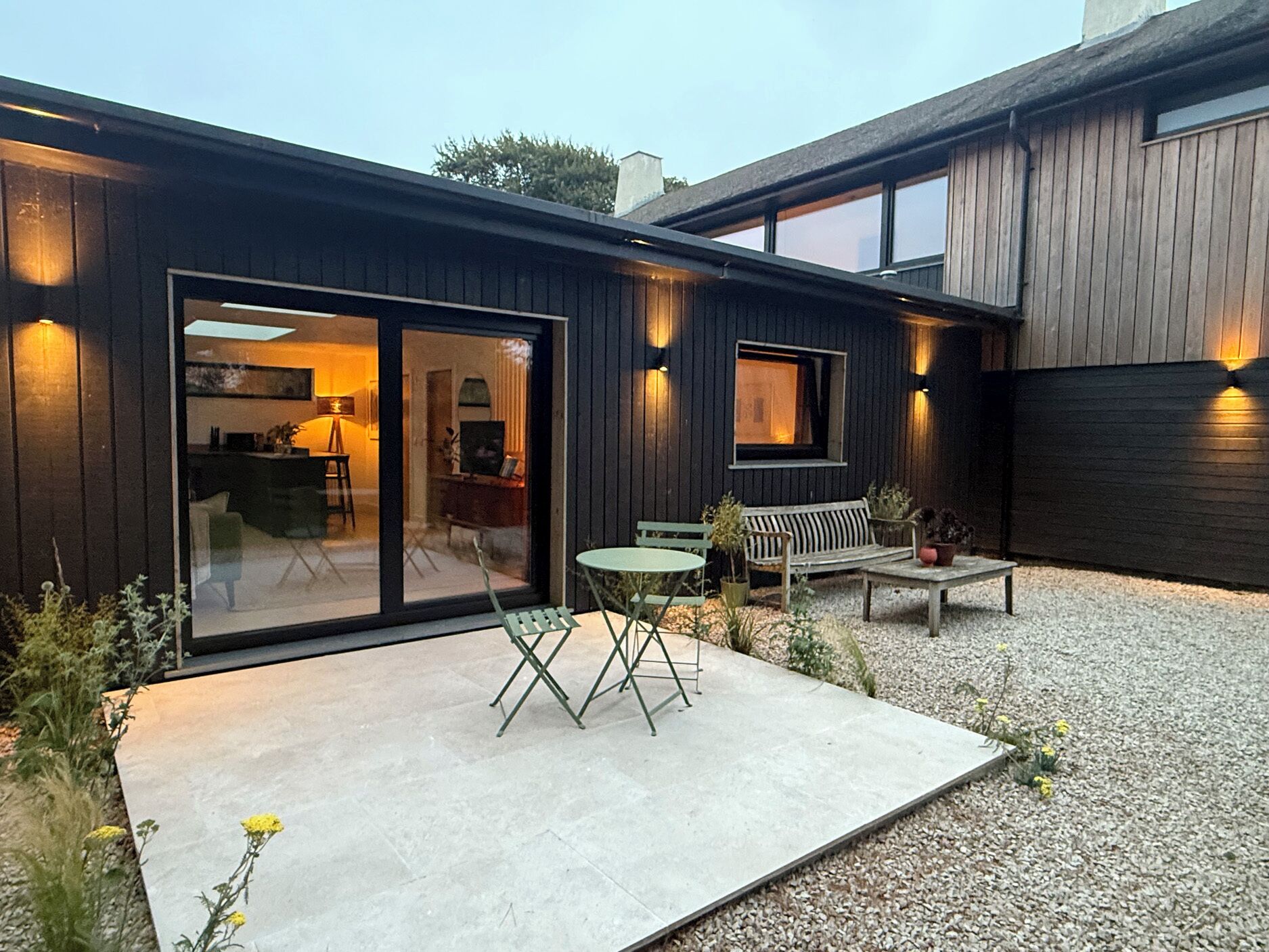 A modern house with a patio, a sliding glass door, and a small table with chairs.