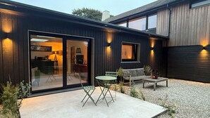 Une maison moderne dotée d’un patio, d’une porte-fenêtre coulissante et d’une petite table avec des chaises.