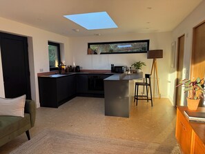Eine moderne Küche mit Oberlicht, einem Essbereich und einem Wohnbereich mit einer Couch.
