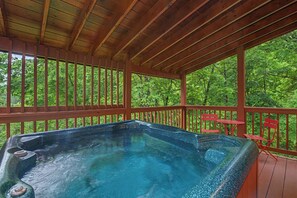 Ein Whirlpool mit Holzterrasse und roten Stühlen, umgeben von einem Hollerdgeschoss.