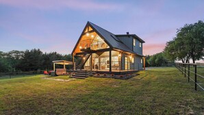 A modern house with a large glass facade, a prominent staircase, and a well-lit interior.