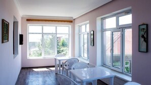 Um quarto com uma janela grande, uma mesa branca e uma cadeira branca.