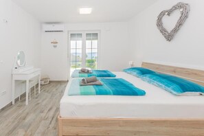Een kamer met twee bedden, een bureau, een spiegel en uitzicht door een deur.