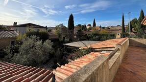 Eine Dachterrasse mit Terrakottafliesen, Steinmauern und umlaufendem Grün.