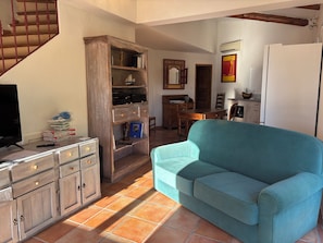 Ein Wohnzimmer mit einer Couch, einem Holzschrank, einem Fernseher und einer Treppe.