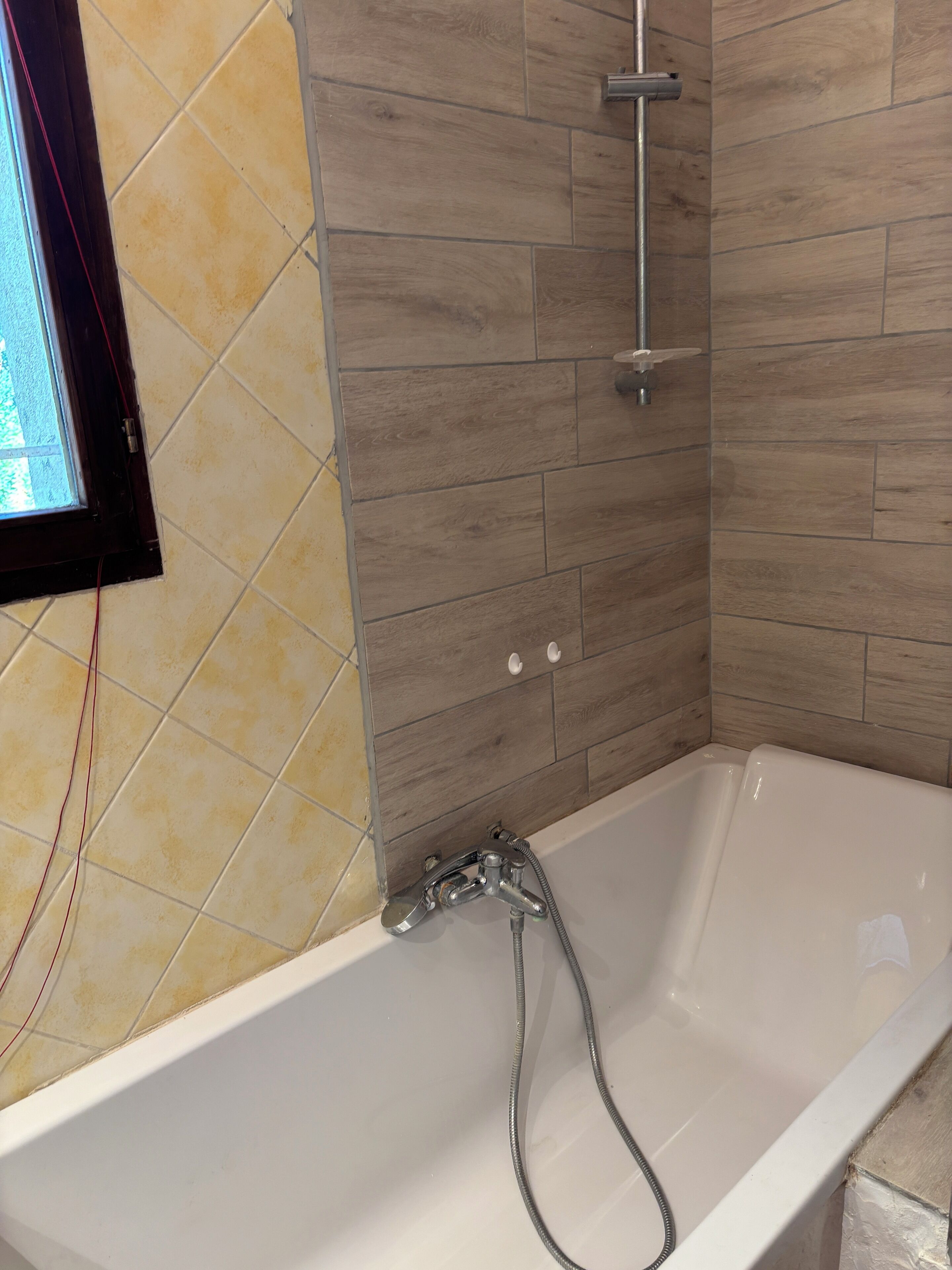 A bathroom with a bathtub, a shower, and a window.
