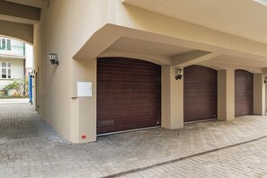 A building with a brick-paved entrance, large wooden garage doors, and a light fixture on the wall. - Havana Premium Family Apartment Sopot (Sopot)