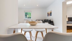 A modern dining area with a white table, four chairs, and a large bowl. - Apartment 'Whg 1.1 EG Links Vorn' with Private Terrace and Wi-Fi (Putbus)