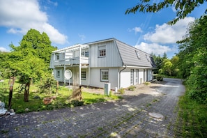A two-story house with a balcony, a paved driveway, and a garden.