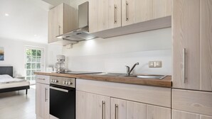 Eine moderne Küche mit hellen Holzschränken, einem eingebauten Ofen und einer Kaffeemaschine.