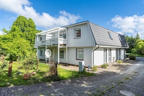 Ein zweistöckiges Haus mit Balkon, Satellitenschüssel und gepflegtem Garten.