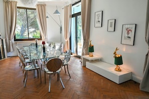 A modern dining area with a glass table, chairs, and pendant lights.