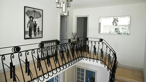 Un escalier orné de rampes noires, une photographie en noir et blanc et un lustre moderne.