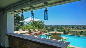 Un espace aménagé au bord de la piscine, avec des chaises longues, une table et des lanternes suspendues.