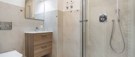 A modern bathroom with a toilet, vanity, and shower.
