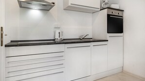 Eine moderne Küche mit weißen Schränken, einer Edelstahl-Dunstabzugshaube, einer Kaffeemaschine und einem Toaster.