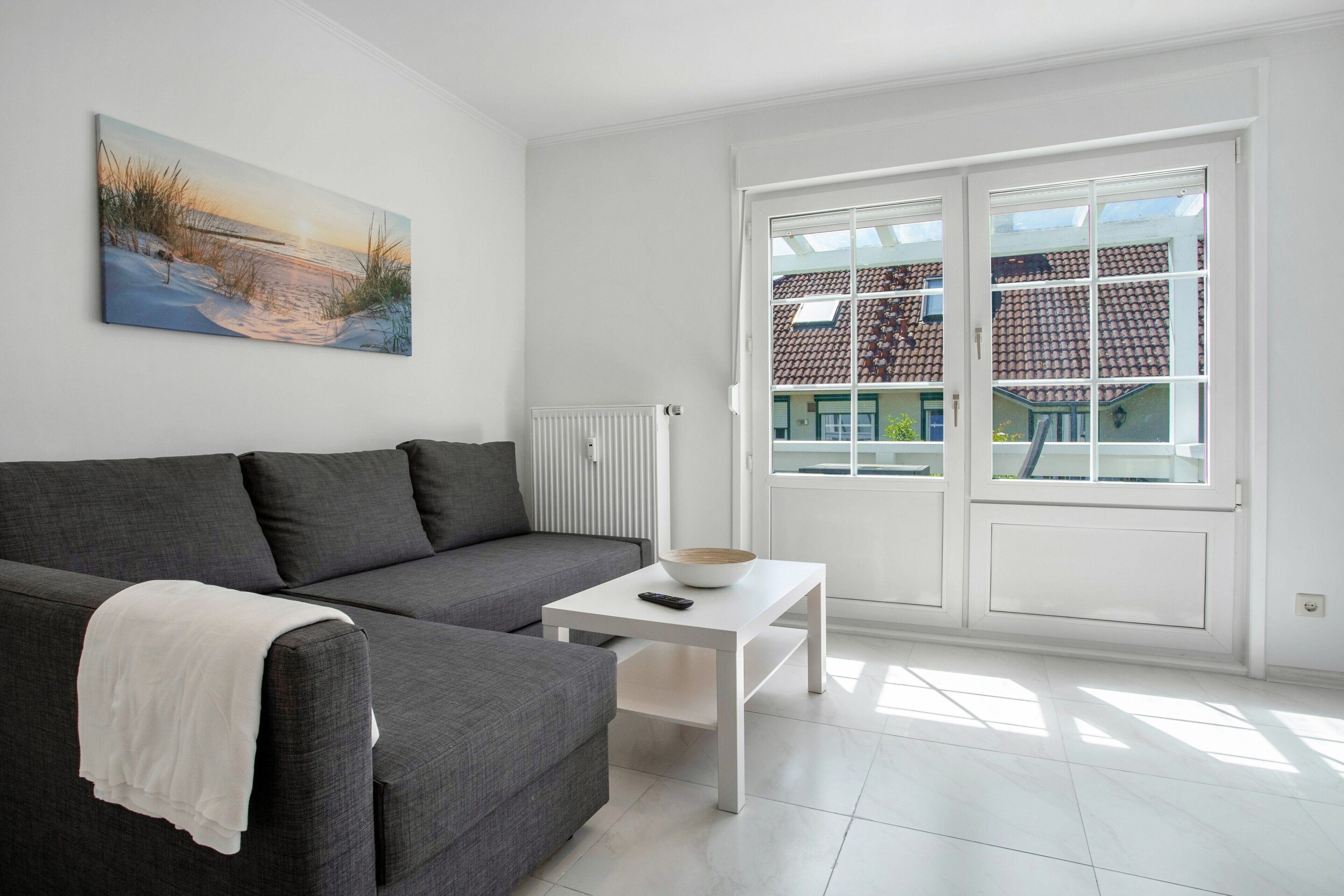 Un salon moderne avec un canapé gris, une table basse blanche et un tableau accroché au mur.