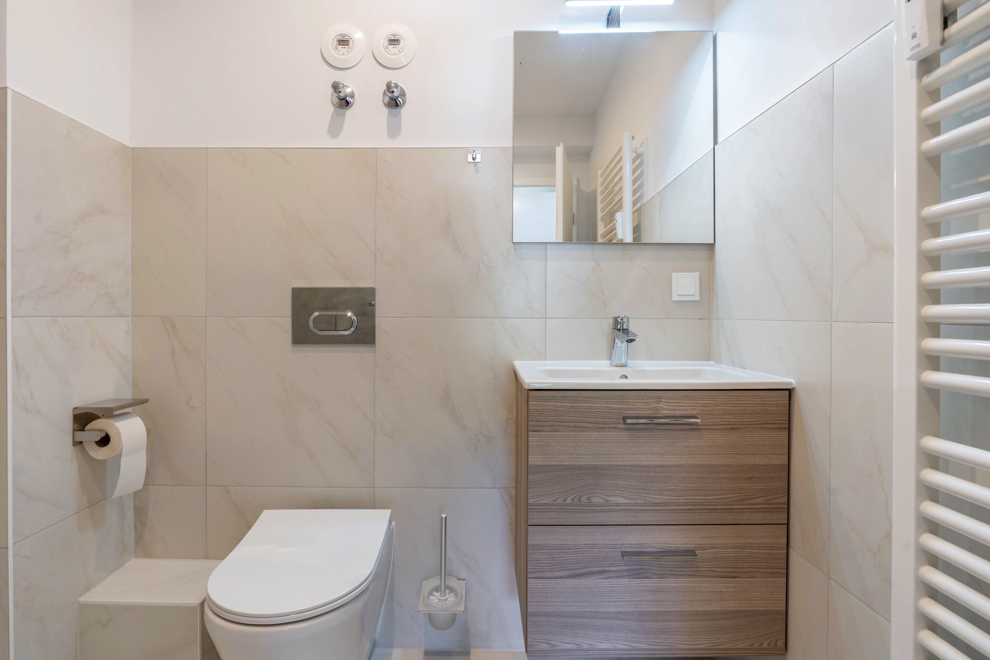 Ein modernes Badezimmer mit Toilette, Waschbecken, Spiegel und Handtuchhalter.