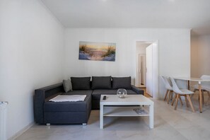 Ein modernes Wohnzimmer mit einer Couch, einem Couchtisch und einem Gemälde mit Strandansicht.