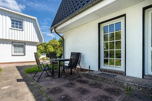 A house with a patio, a table with chairs, and a door with a window. - Apartment 'WE14 EG Links Hinten' with Private Terrace and Wi-Fi (Putbus)