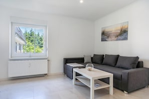 Ein modernes Wohnzimmer mit einem grauen Sofa, einem weißen Couchtisch und einem Gemälde an der Wand.