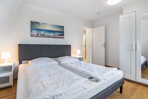 Makuuhuoneessa on sänky, yöpöydät, yölamppu, vaatekaappi ja taulu seinällä.