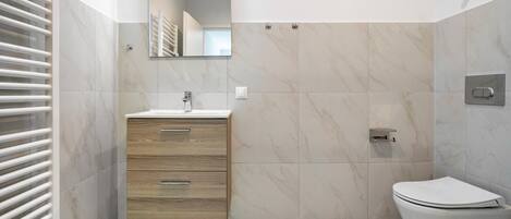 Une salle de bain moderne avec un meuble-lavabo en bois, des toilettes et une douche.
