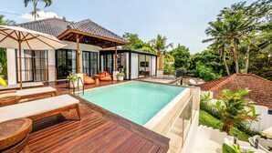 A modern villa with a swimming pool, wooden deck, and lush tropical surroundings. - Villa Oasis (Ubud)