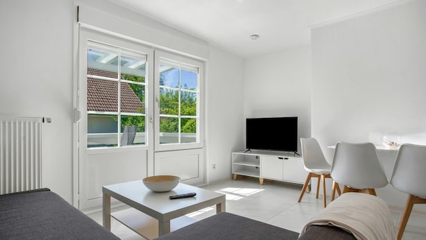 A modern living room with a TV, sofa, and dining area. - Apartment 'Whg 2.8 1.OG Rechts Hinten' with Balcony (Putbus)