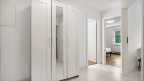 Ruime kamer met een grote kast, een bed op een houten vloer, en een raam met uitzicht op groen.