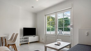 Een moderne woonkamer met een flatscreen televisie, een eethoek met stoelen, een bank en een tafel.