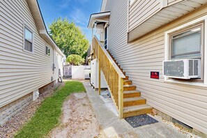 Un quartier résidentiel avec un escalier en bois menant à une maison, un panneau « Il est interdit de fumer » et un appareil de climatisation sur le côté.