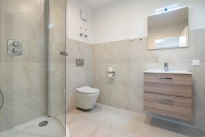 Une salle de bain moderne avec une douche à parois de verre, des toilettes et un meuble-lavabo avec des tiroirs.