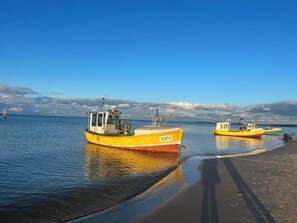 Una playa con barcos amarrados, cielos despejados y aguas tranquilas.
