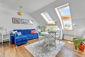 Un loft moderno con un sofá azul, una mesa de comedor y un tragaluz grande.