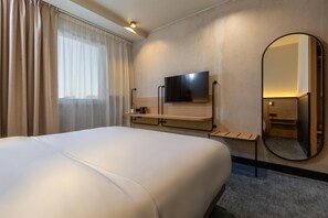 A hotel room with a large bed, a flat-screen TV mounted on the wall, a bedside table, a mirror, and a window with curtains. - Tulip Hotels & Residences - Marseille Aubagne (Aubagne)