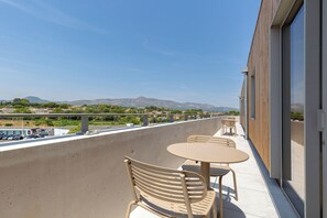 A balcony with outdoor seating and a view of a mountainous landscape.