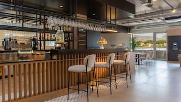 Een bar met een koffieapparaat, flessen op planken en glazen die hangen.