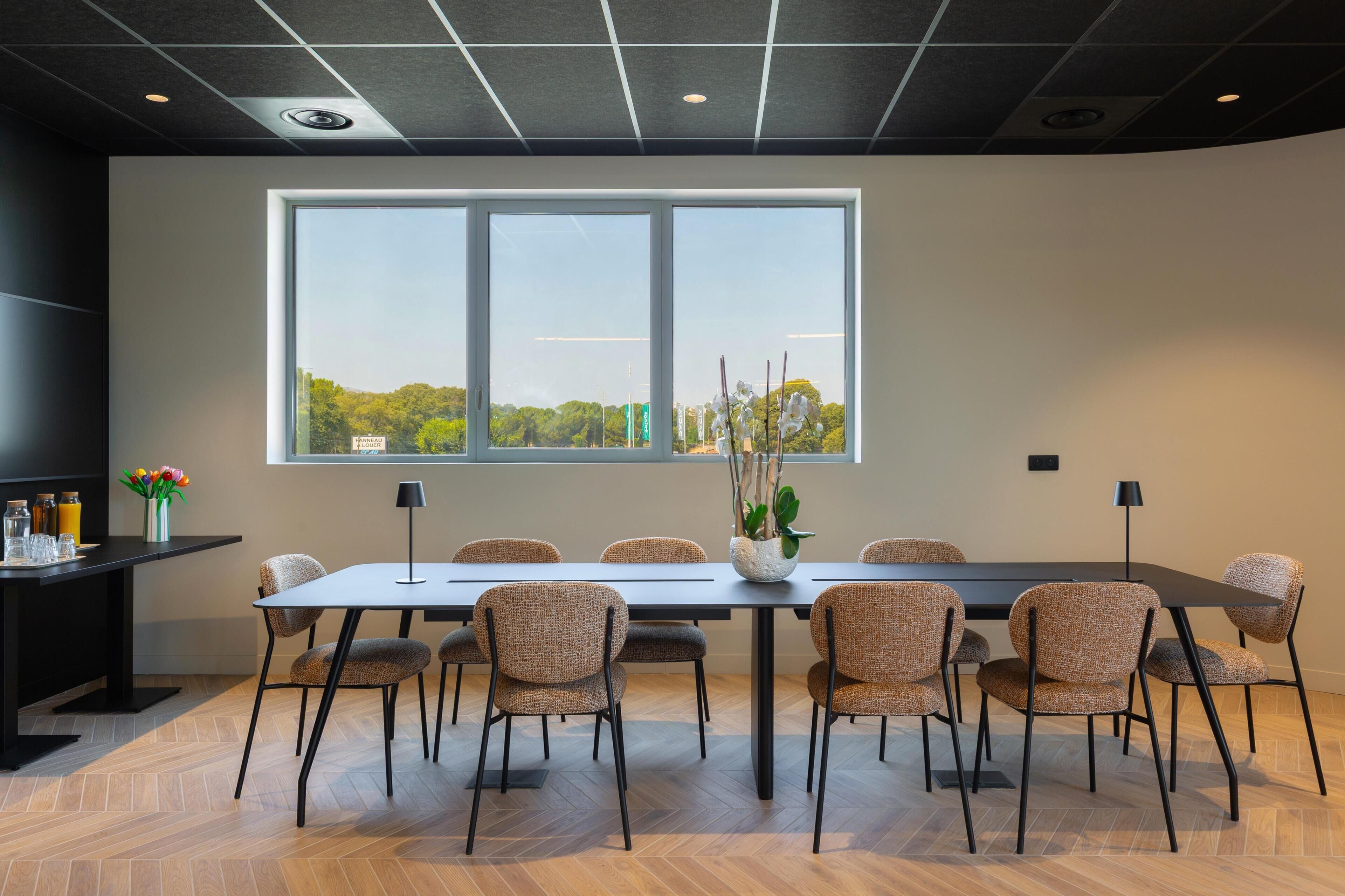 Een vergaderruimte met een groot raam, een lange tafel en zes stoelen.
