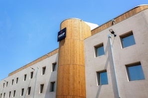 Un hotel moderno con fachada de madera cilíndrica y un letrero que indica que es hotel y residencia.